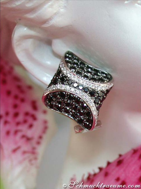 Schwarz-weiß-diamantierte Ohrstecker in Weißgold, Detailaufnahme auf Porzellanbasis.