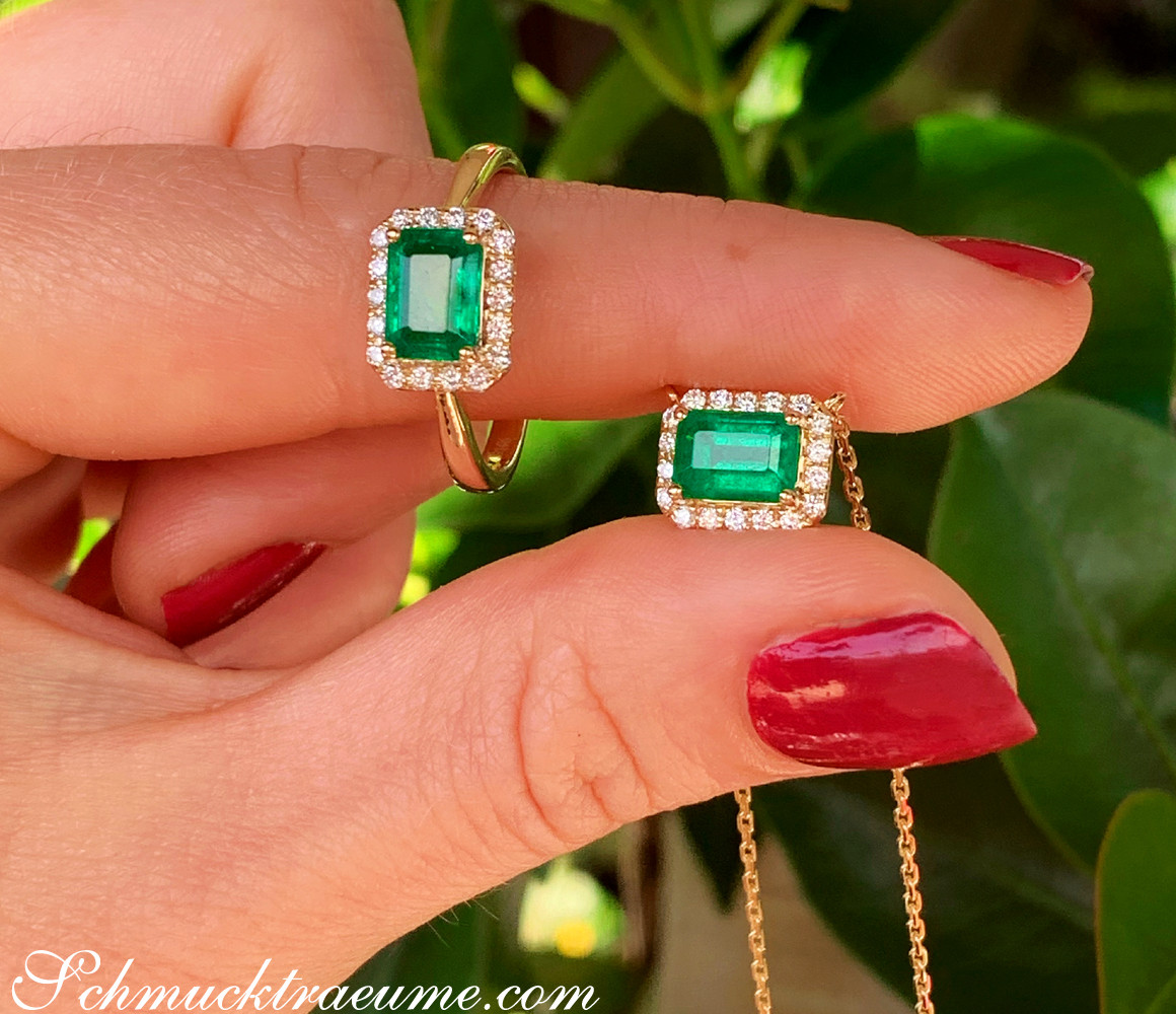 Smaragd-Ring mit Brillanten auf Finger, grüner Hintergrund, Nagellack rot