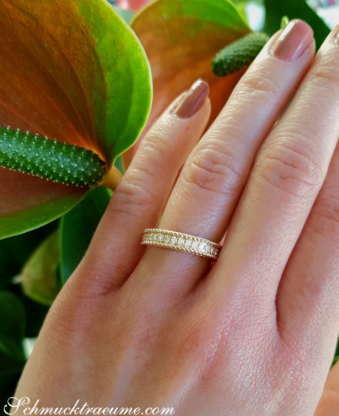 Goldener Diamant-Ring mit Kordel-Design auf grünen Blättern