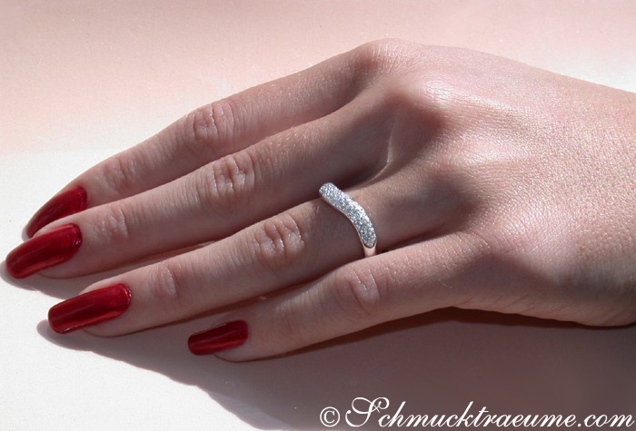 Geschwungener Diamant-Ring auf Hand mit roten Nägeln