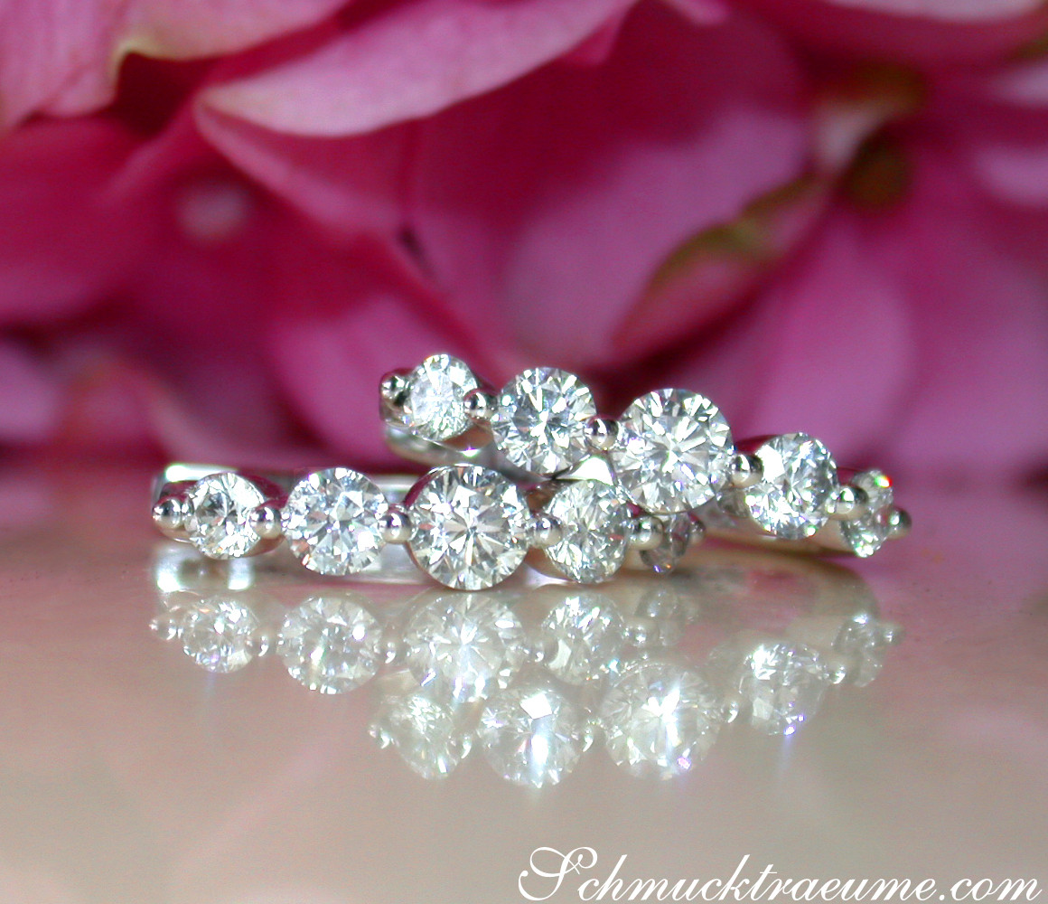 Weißgold-Ohrringe mit 10 Brillanten, die sich nach innen vergrößern, auf glänzender Oberfläche.