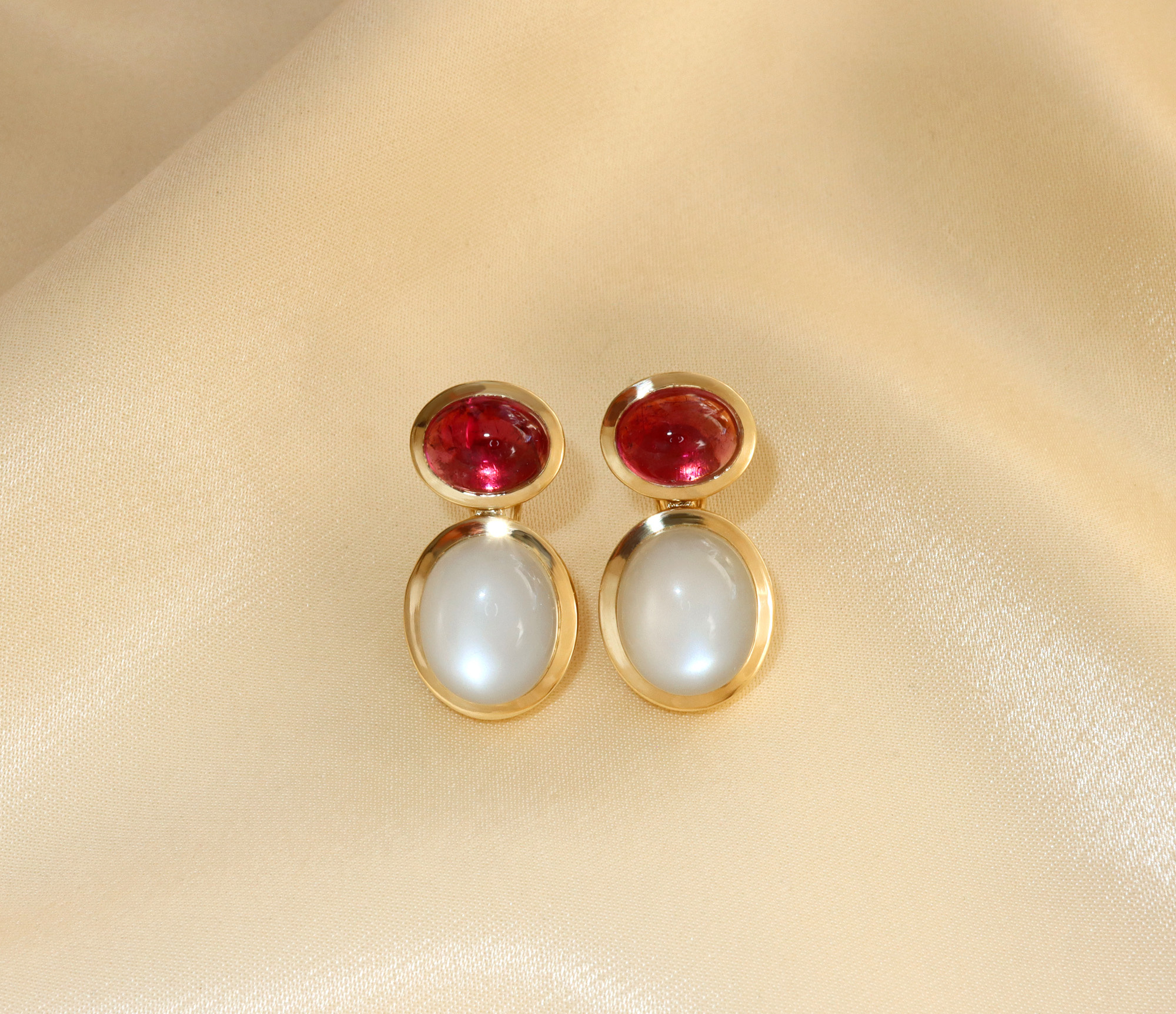 Rubellit-Mondstein-Ohrhänger in Gelbgold, elegant auf beige Stoff ausgelegt