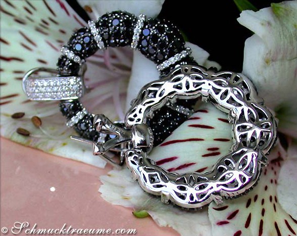 Detailaufnahme von Ohrringen mit schwarzen und weißen Diamanten auf Blüte liegend