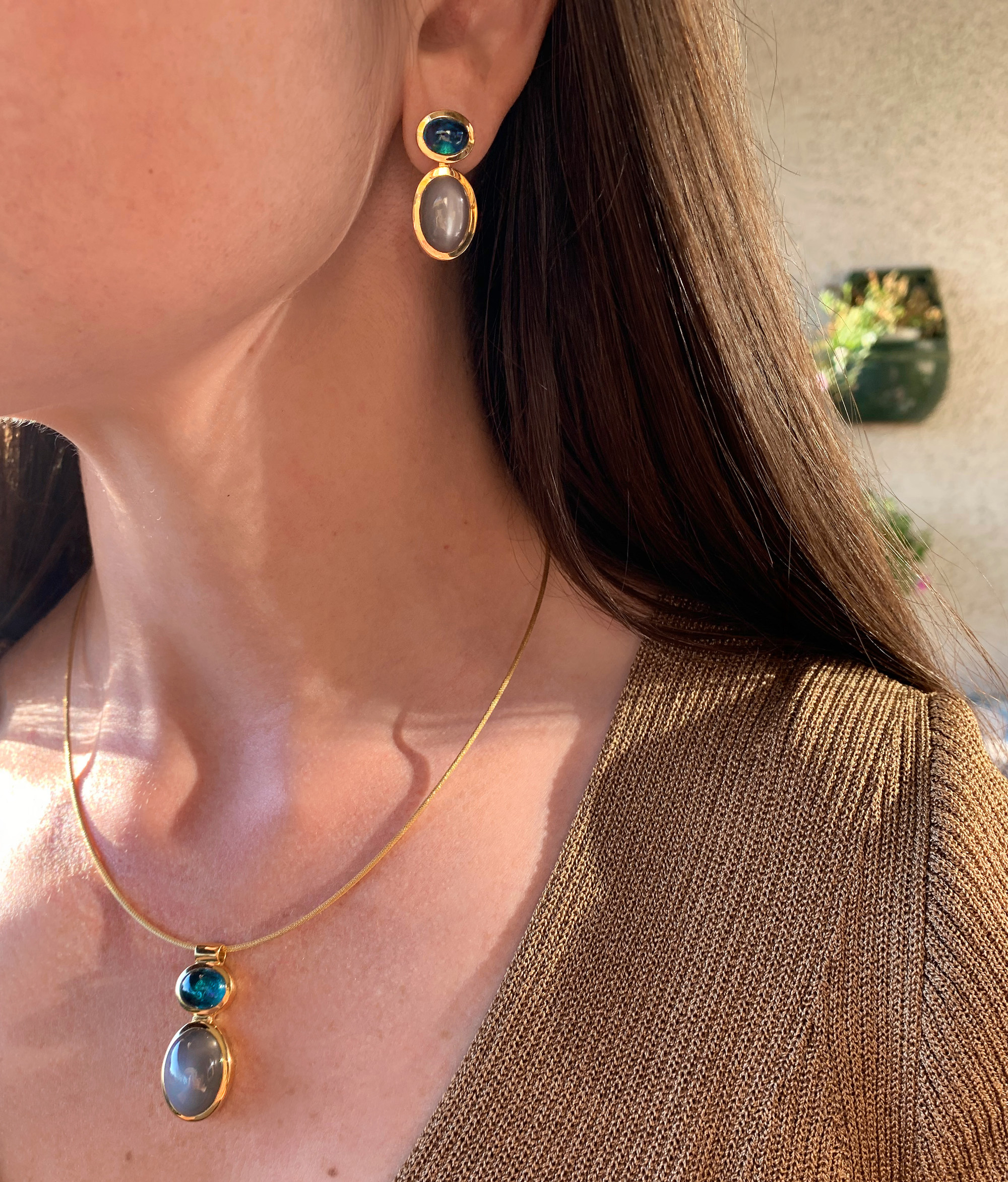 Goldene Ohrringe mit Mondsteinen, getragen am Hals, Detailaufnahme