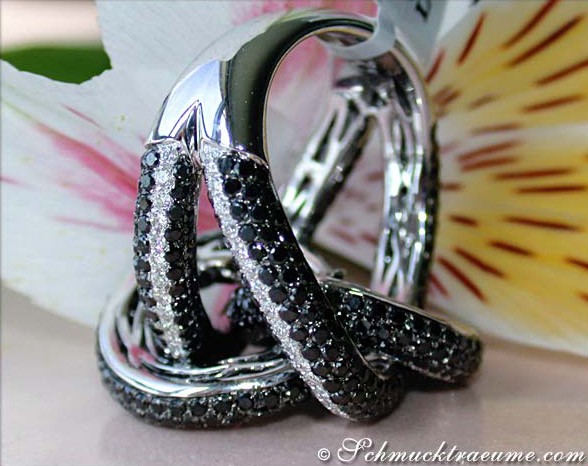 Schwarze Diamant-Ringdetail auf Goldbasis, elegant geschwungen, Blume im Hintergrund.