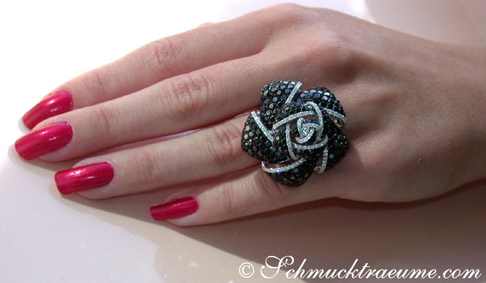 Rosenformiger Ring mit schwarzen Diamanten auf Hand, Nagellack rot