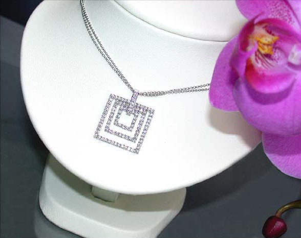 Kunstvoller quadratischer Diamantanhänger an Kette auf weißem Halsringmodell mit Orchidee im Hintergrund