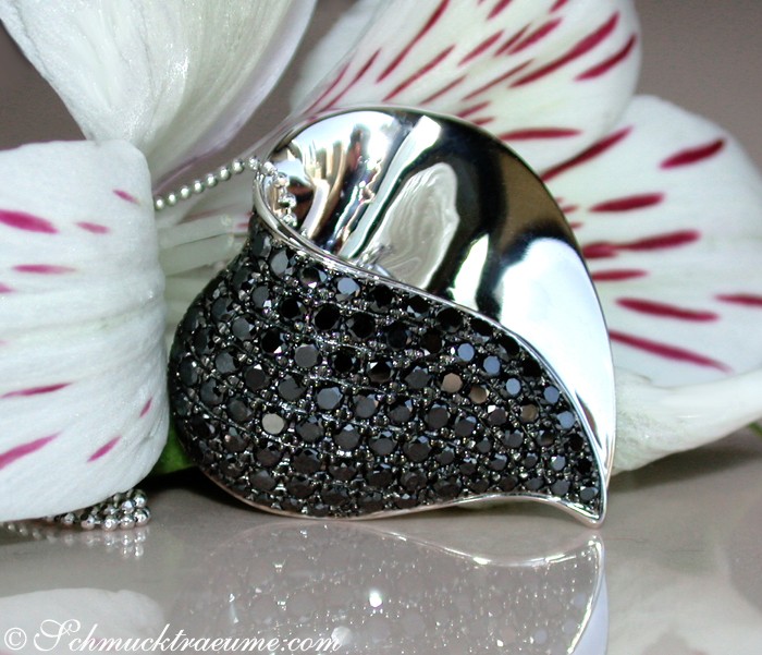 Schwarzer Diamant Herzanhänger mit Weißgold, Detailaufnahme, elegant, feminin, dunkle Perlen, Orchideenblüte im Hintergrund