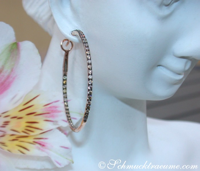 Mannequin mit roségoldenen Creolen und Blume im Hintergrund