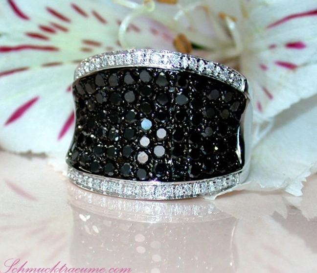Weißgoldring mit schwarzen Diamanten und Diamantbesatz, Detailaufnahme, Blüten im Hintergrund Weißgoldring mit schwarzen Diamanten und Diamantbesatz, Detailaufnahme, Blüten im Hintergrund