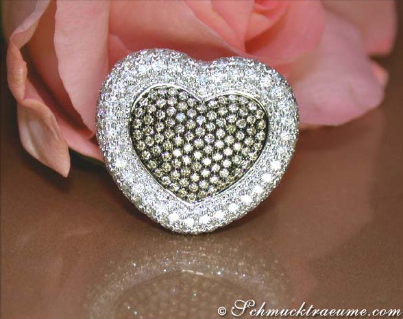 Herzring aus Weißgold mit braunen und weißen Brillanten, detailreich, auf Rosenblüte liegend.