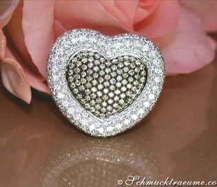 Herzring aus Weißgold mit braunen und weißen Brillanten, detailreich, auf Rosenblüte liegend.