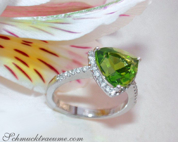 Peridot-Ring mit Brillanten in Weißgold 585, Detailaufnahme mit Blüte im Hintergrund