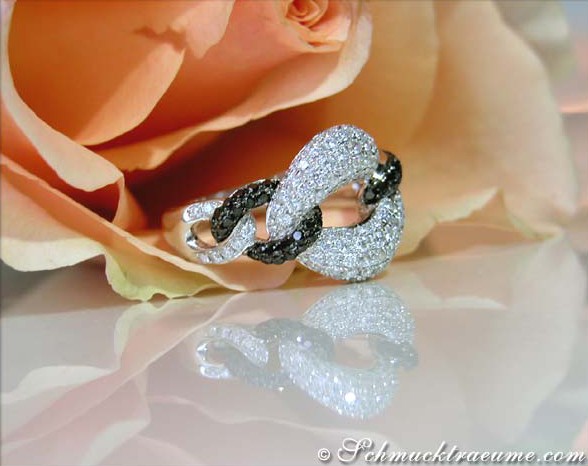 Schwarz-weißer Diamantring mit Gliederdesign, Rosenblüte im Hintergrund