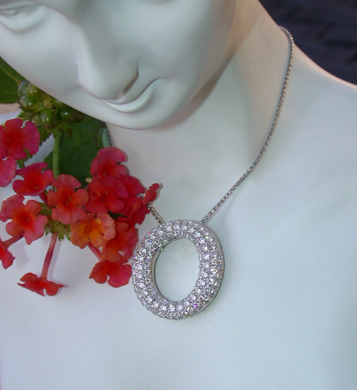 Kreisförmiger Brillanten-Anhänger auf Halsbügel, umgeben von Blüten