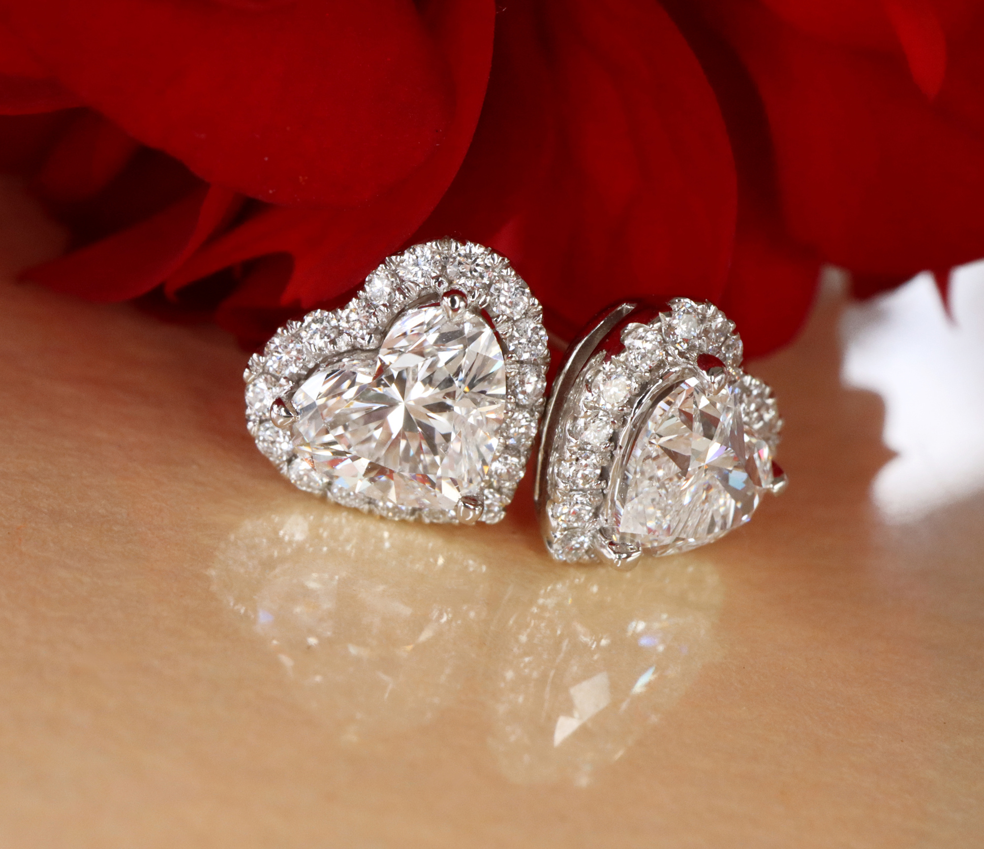 Diamant-Ohrringe in Herzform mit Halo-Design auf Holz mit rotem Hintergrund