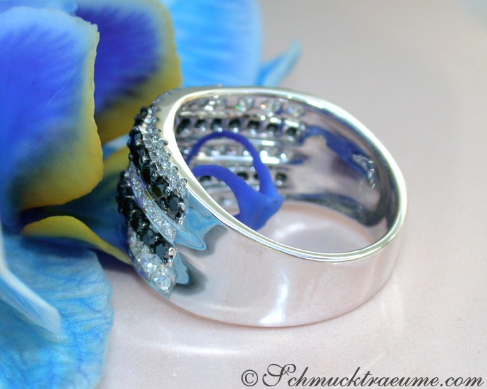 Blauer Orchideenblütenhintergrund mit elegantem schwarzen Diamantenring in Weißgold.