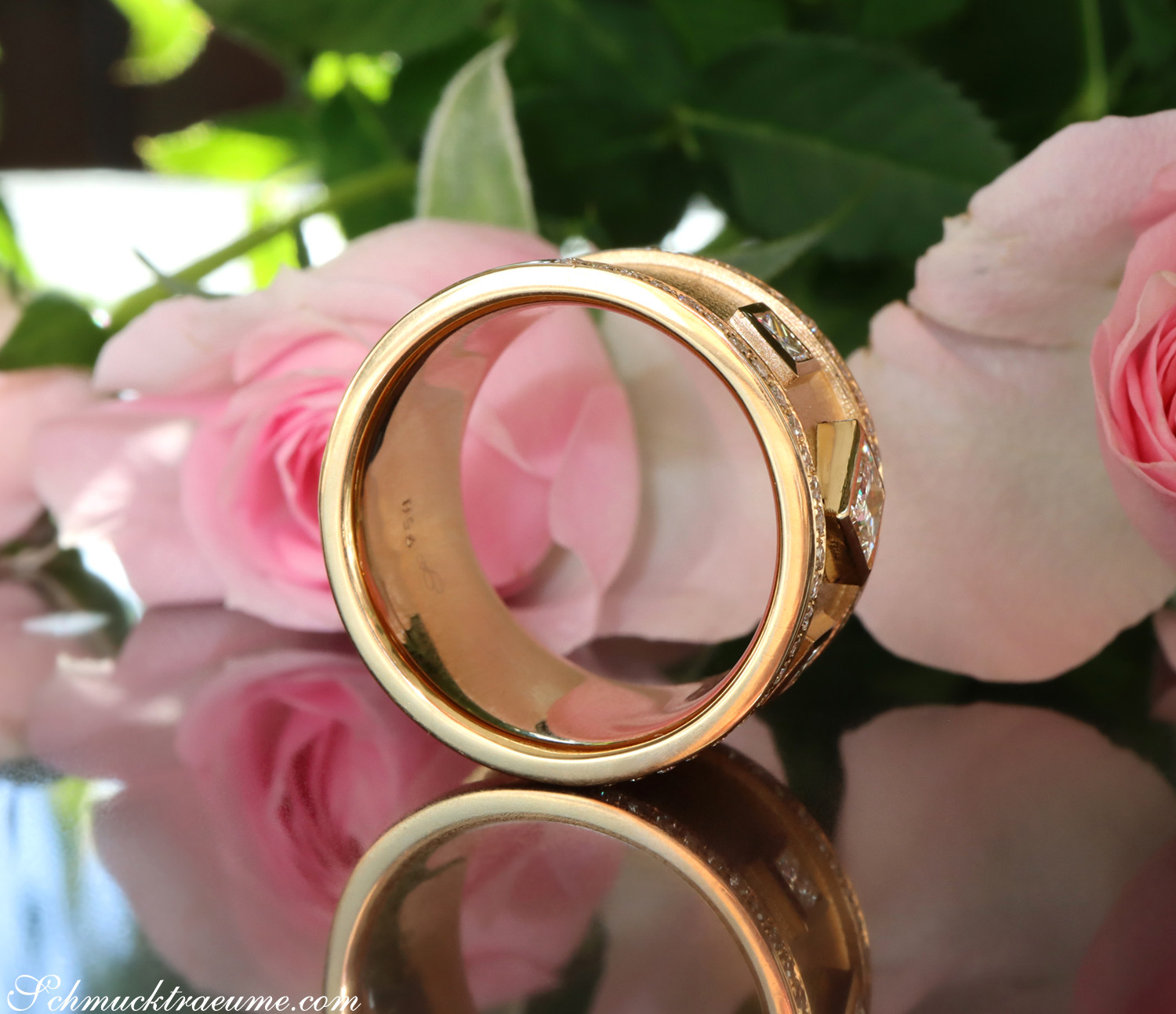 Goldene Ringe mit Diamanten vor Rosenblüten
