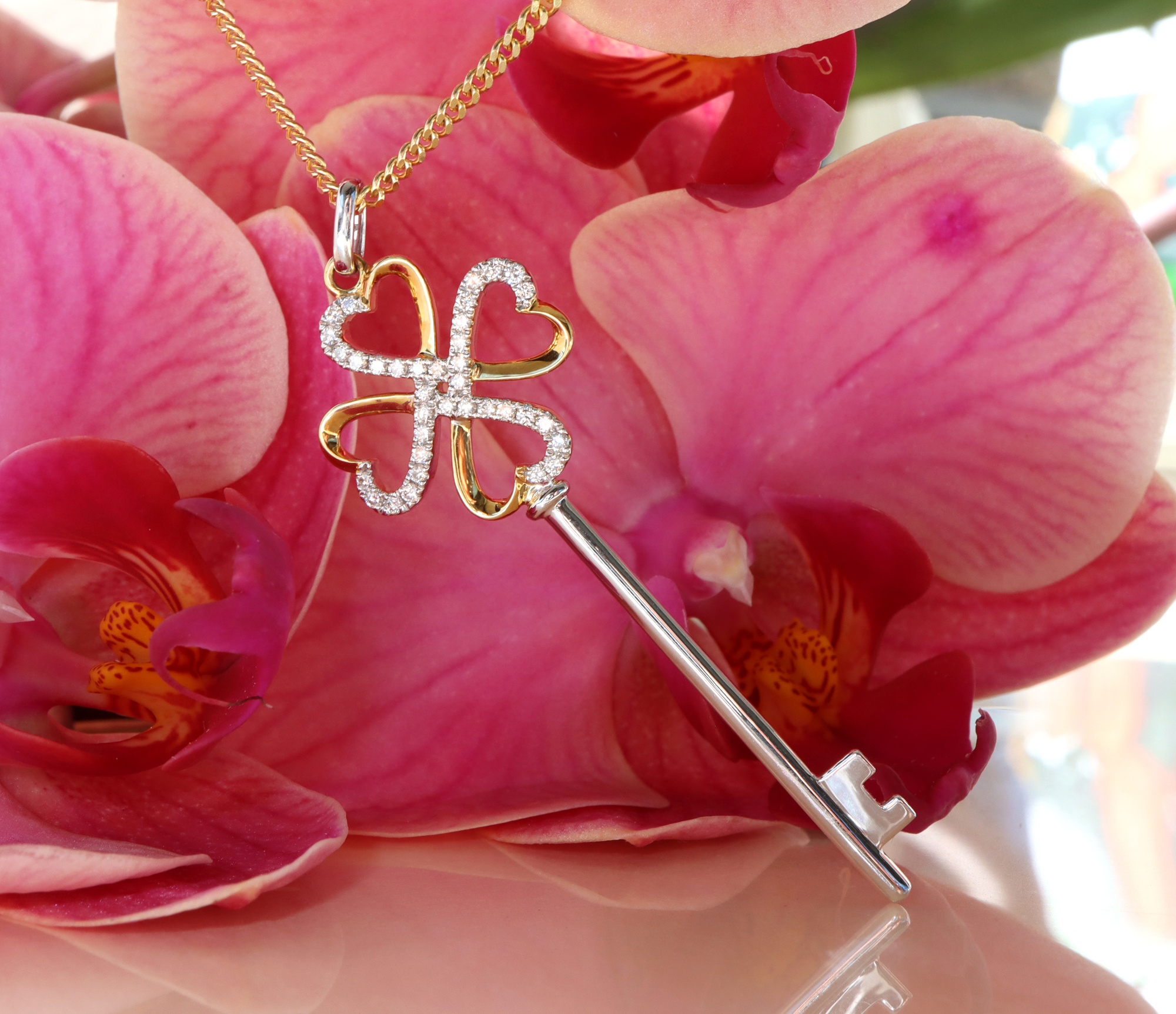 Blumenhintergrund mit Orchideenblüte und goldenem Schlüsselanhänger mit Diamanten.