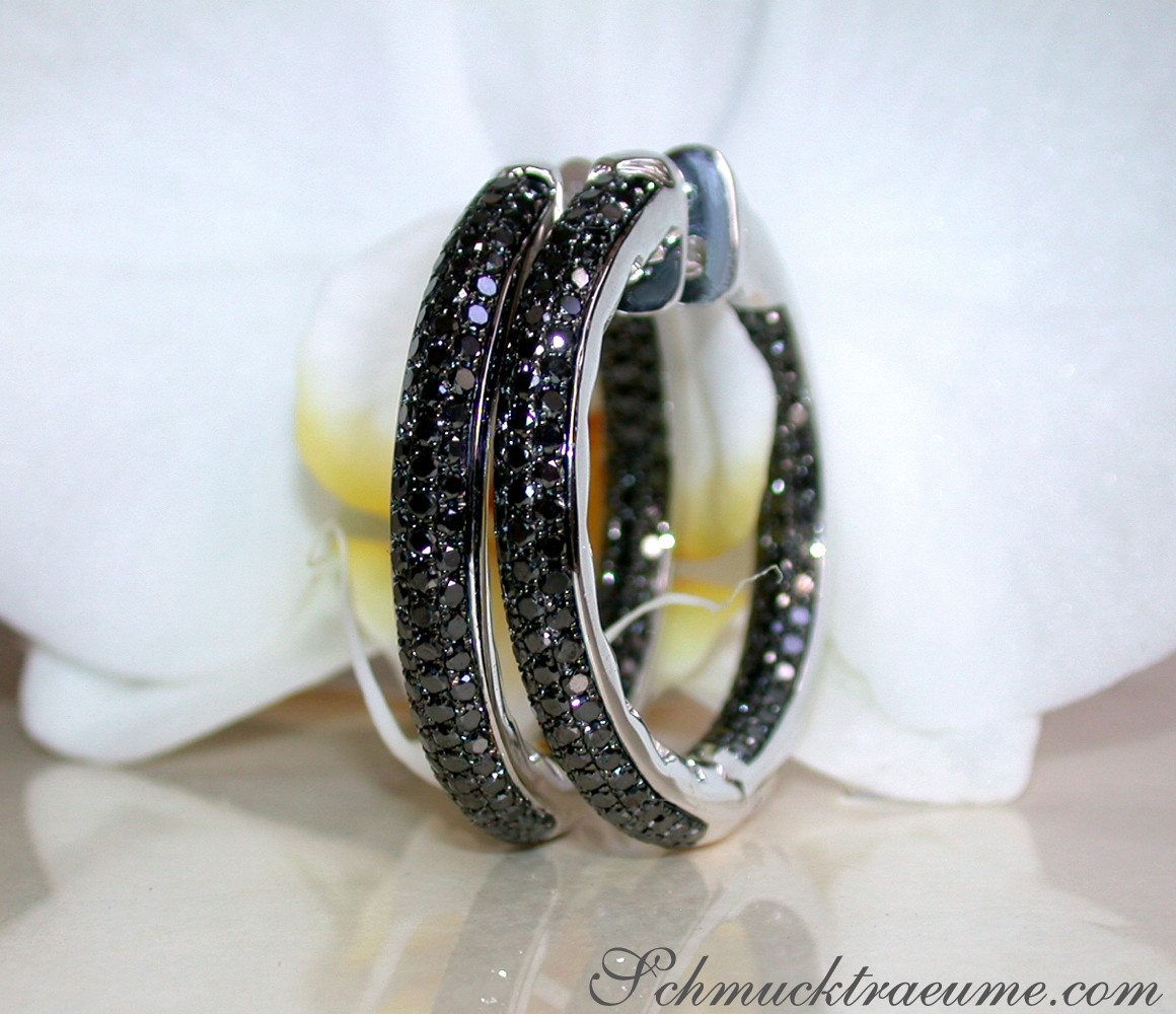 Detailansicht von Creolen mit schwarzen Diamanten auf weißer Blüte