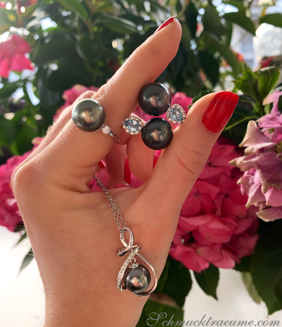 Raffinierter Perlenohrring mit Aquamarinen und Diamanten, im Hintergrund Blüten.