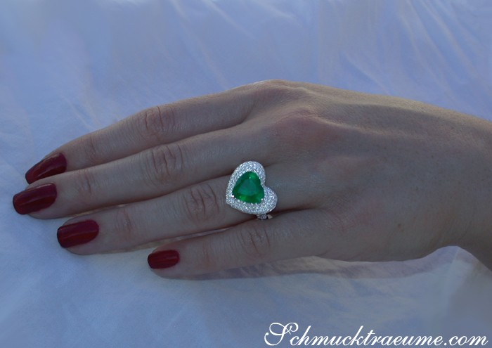 Weißgold Herz-Smaragd-Ring mit Brillanten, Detailansicht auf Hand, dunkelrote Nägel.
