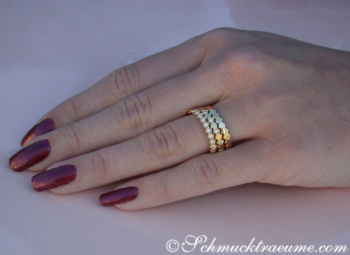 Goldener Diamant-Ring mit Hexagon-Muster auf Hand mit lackierten Nägeln
