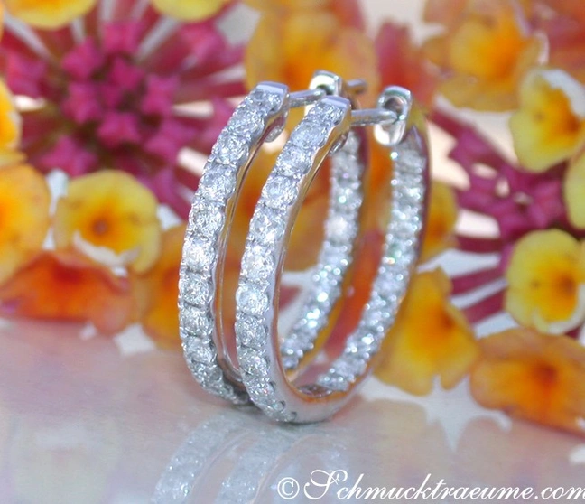 Weißgold 585 Creolen mit Brillanten, Detailaufnahme, blühende Blumen im Hintergrund Weißgold 585 Creolen mit Brillanten, Detailaufnahme, blühende Blumen im Hintergrund