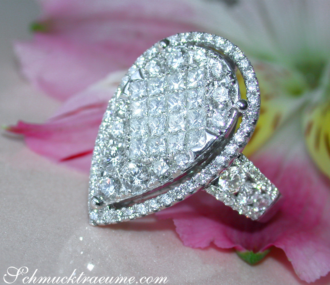 Diamant-Tropfen-Ring mit Princess- & Brillantschliff, detailreich, auf Blume liegend