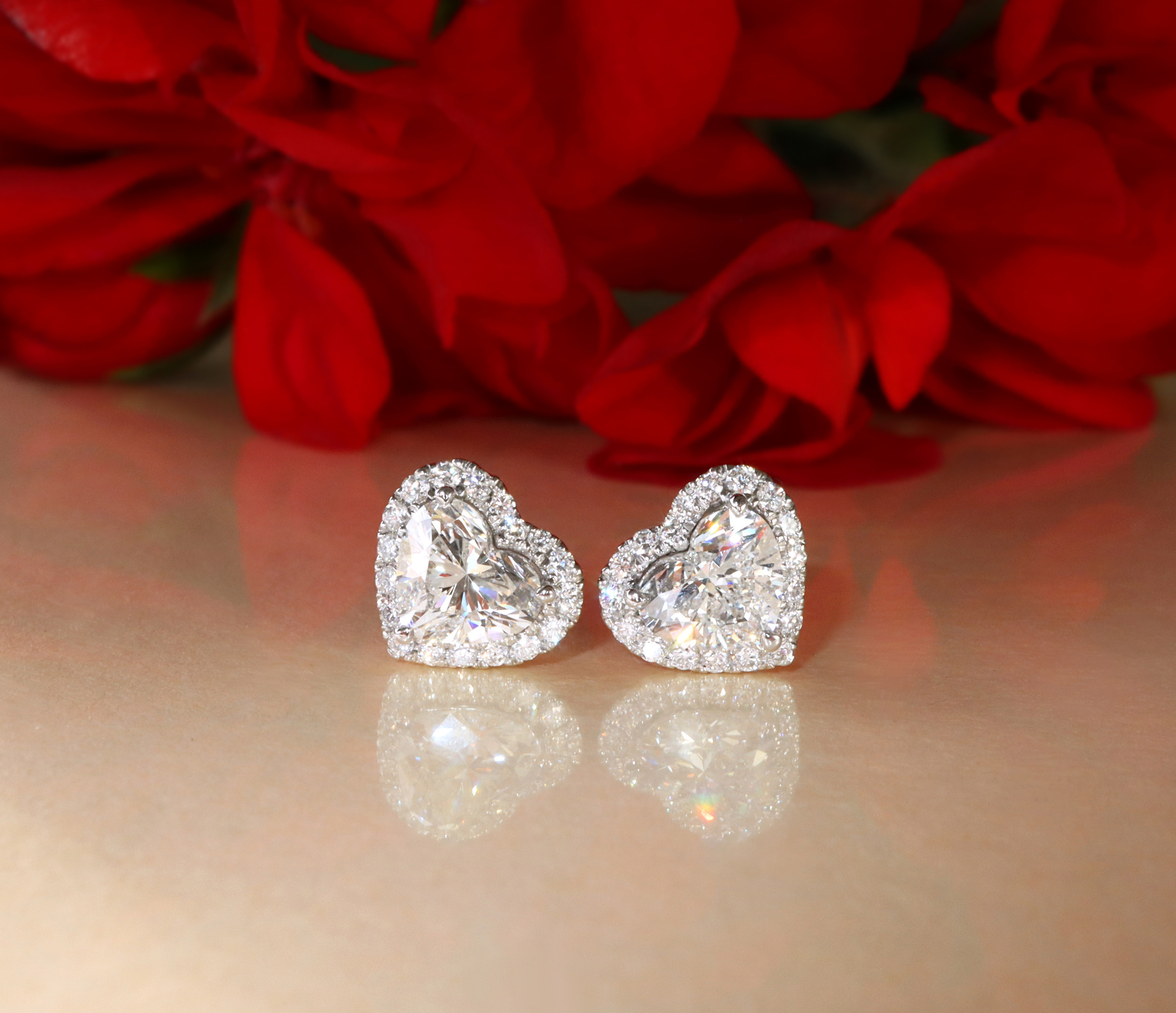 Herzformige Diamantohrringe mit Brillanten auf rosafarbenem Untergrund