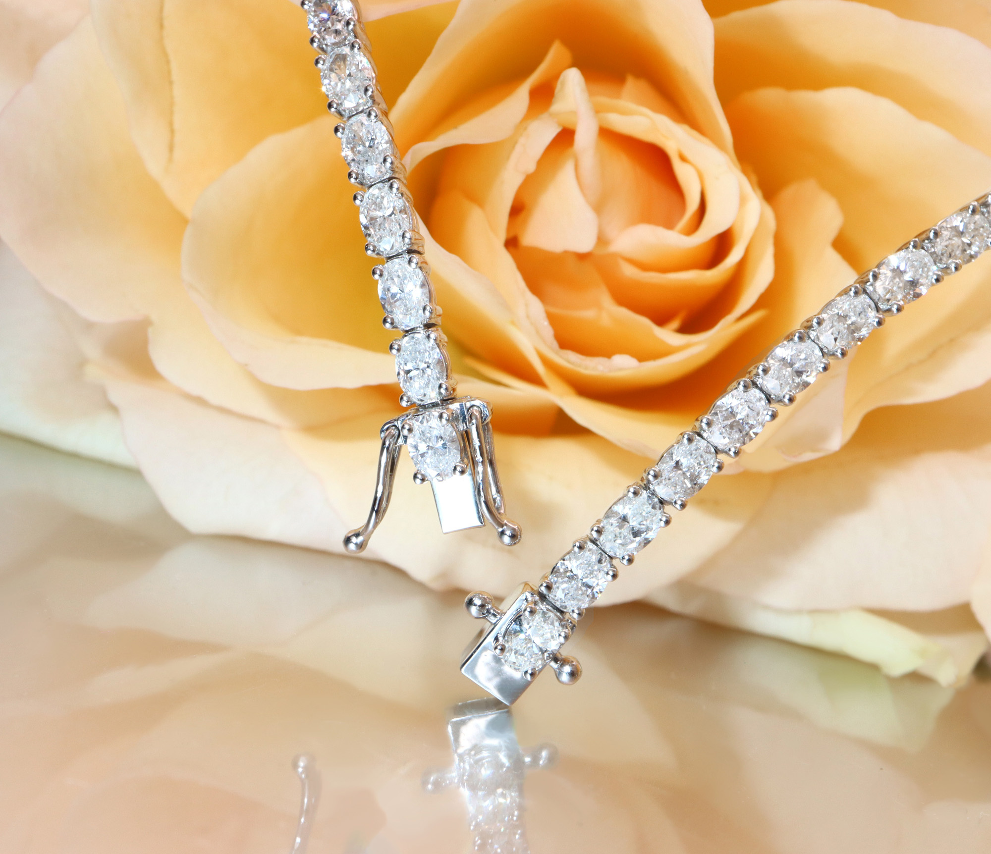 Detailbild eines Tennisarmbandes mit ovalen Diamanten auf Rosenblüte