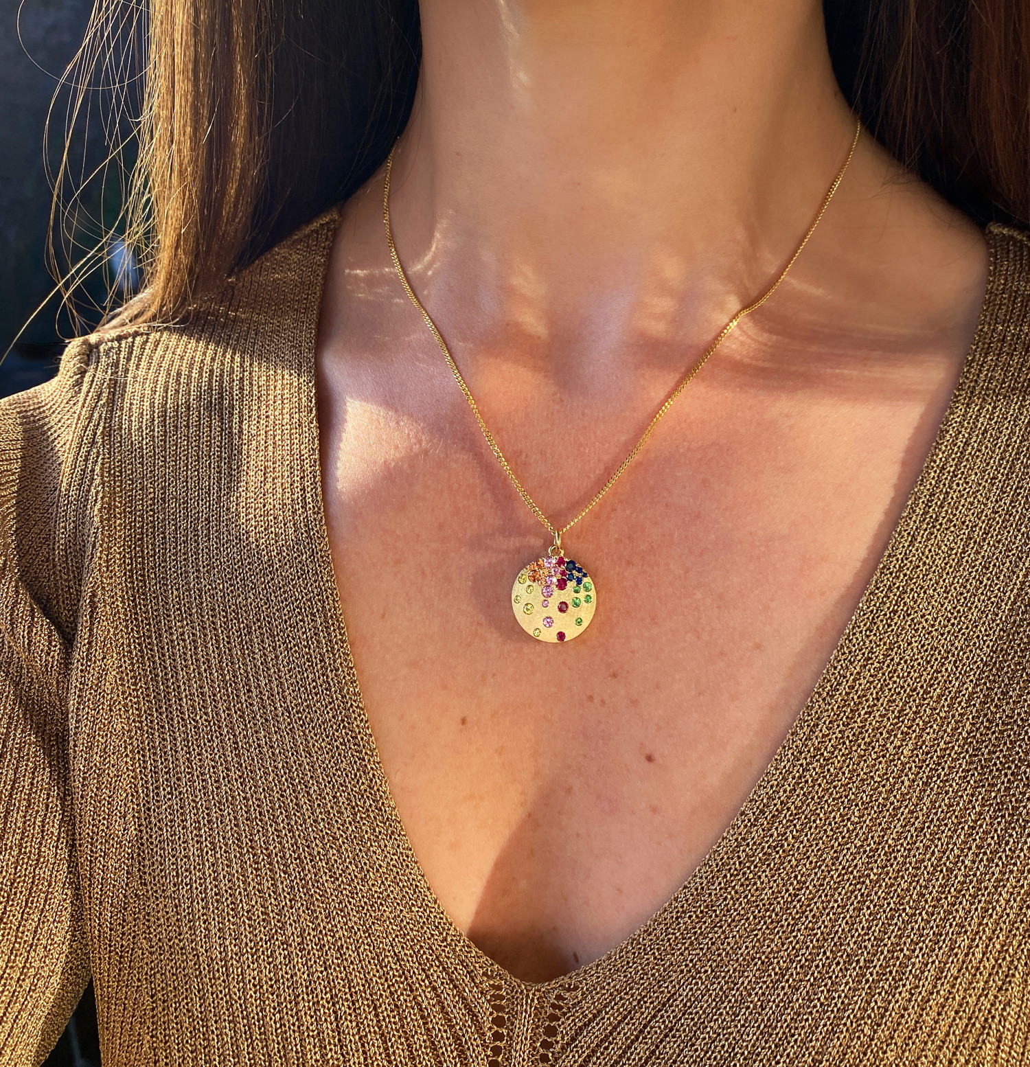 Goldene Halskette mit farbenfrohem Saphir-Medaillon getragen