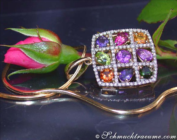 Goldener Anhänger mit farbenfrohen Edelsteinen und Diamanten, Detailaufnahme, Rosenblüte im Hintergrund