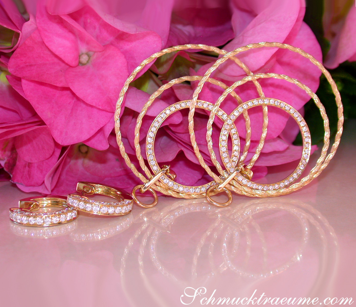 Gelbgold Kreisohrringe mit Brillanten, Detailaufnahme vor rosa Blüten.