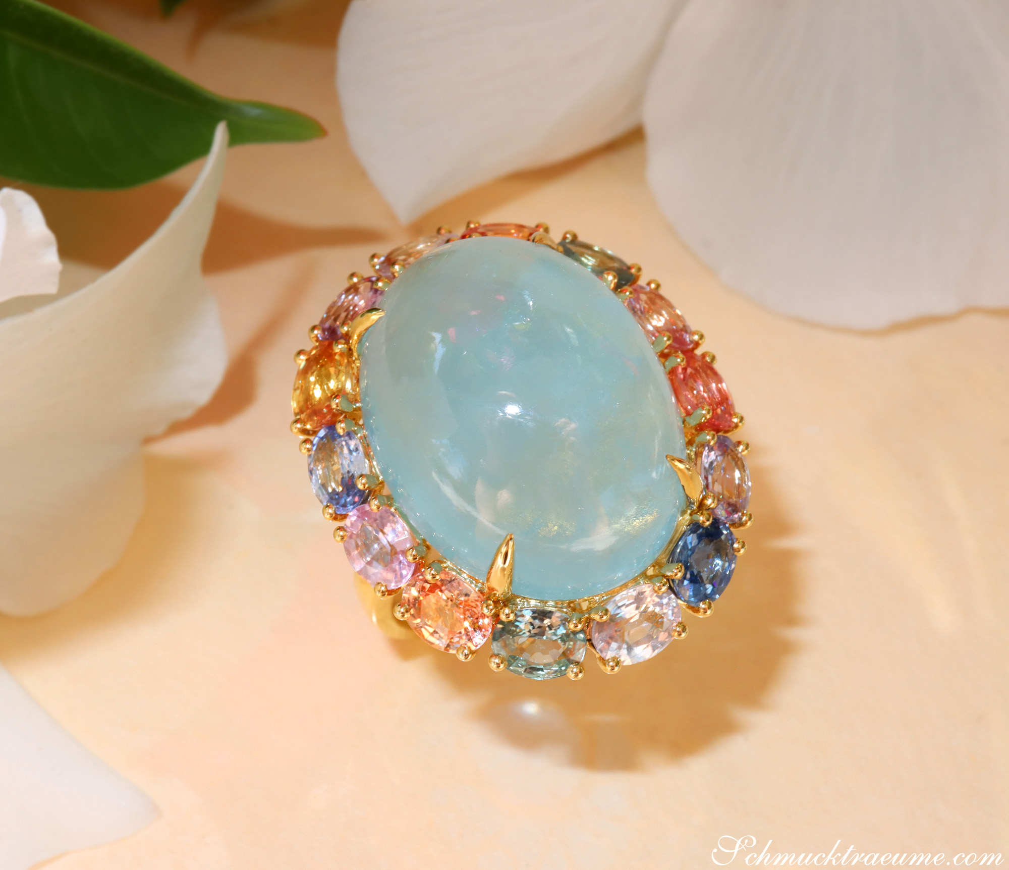 Goldener Ring mit ovalem Milky Aquamarin und pastellfarbenen Saphiren, detailreich, auf Blüte abgestellt