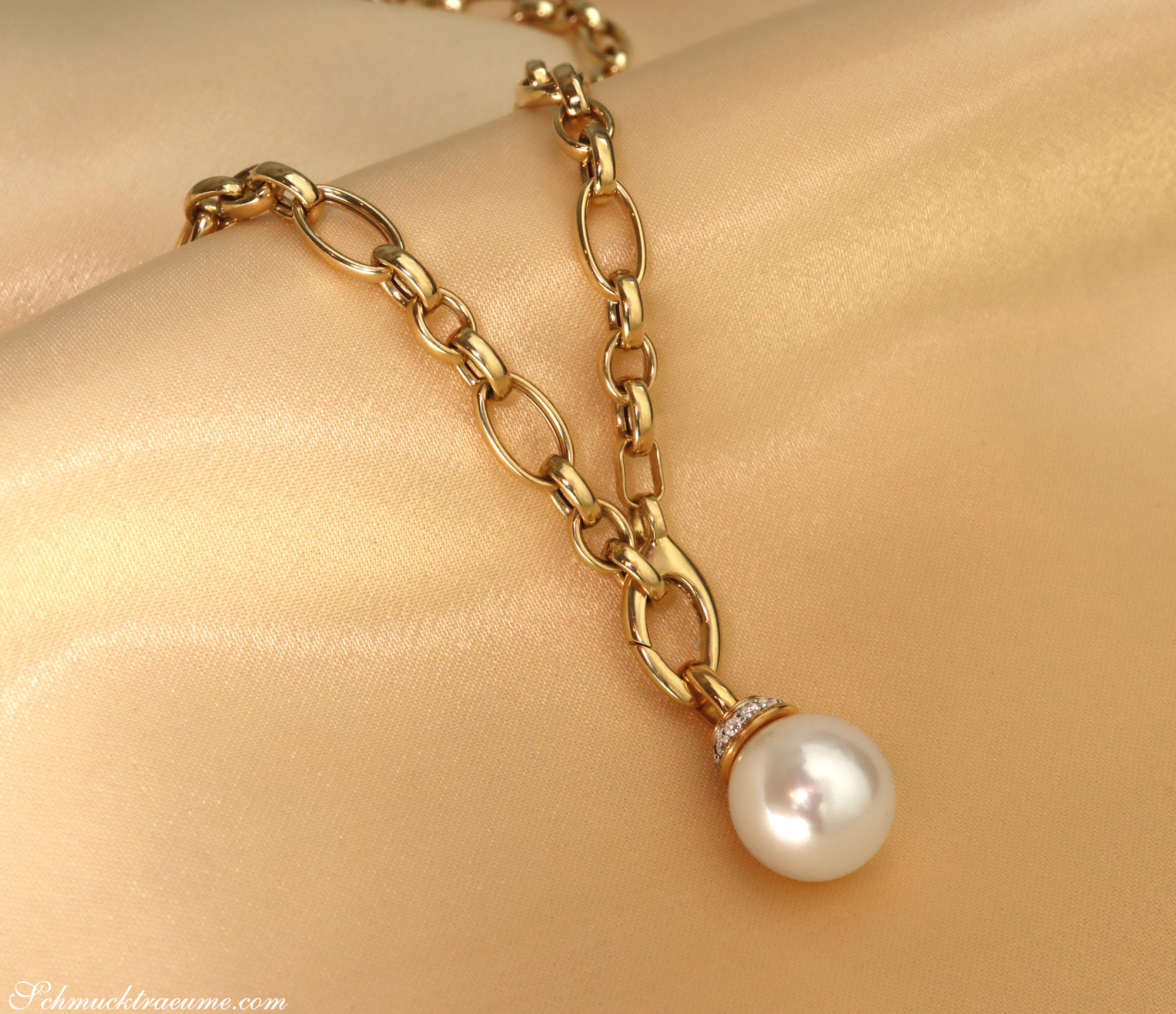 Goldkette mit Perle und Diamanten, Detailaufnahme auf goldenem Stoff, elegant und luxuriös.