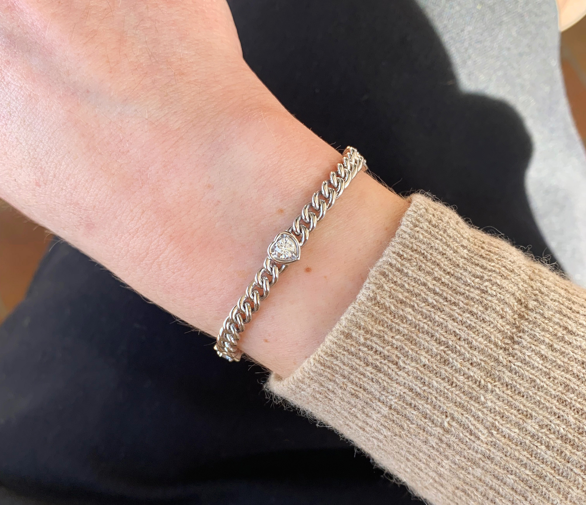 Weißgoldarmband mit Herz-Brillanten, Detailaufnahme auf Hand, Pulloverarm sichtbar