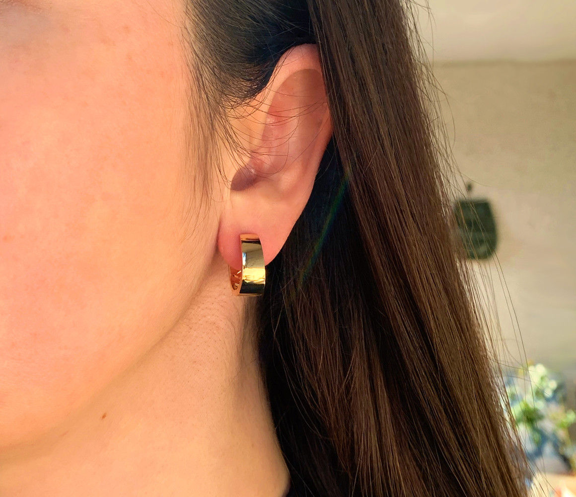 Goldene Ohrringe mit Saphir und Rubinen, Detailaufnahme von Ohr und Ohrring.