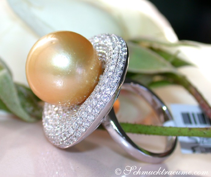 Weißgoldring mit goldenem Perlenkern, umgeben von Diamanten, Detailaufnahme, elegant getragen.