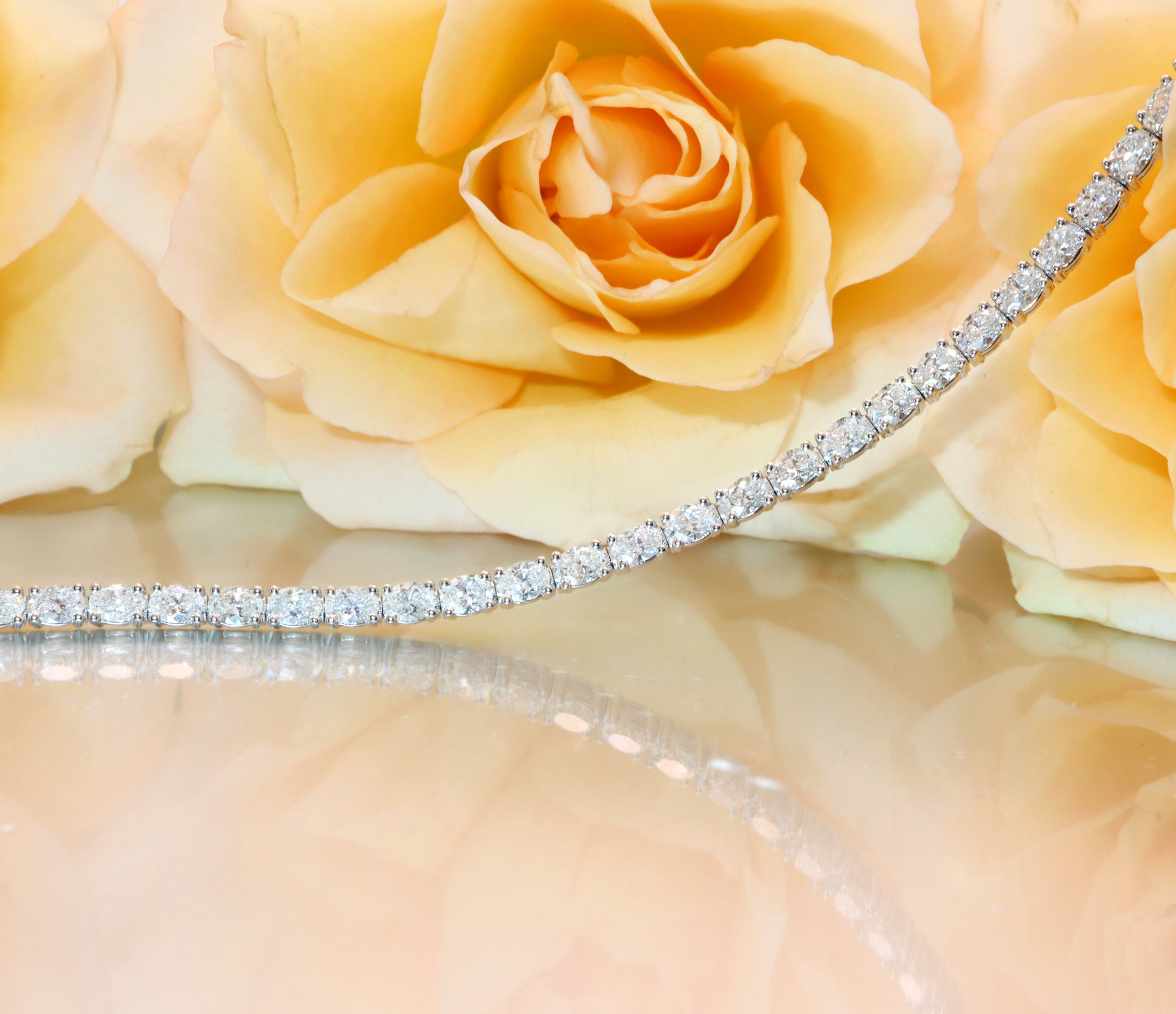 Goldenes Tennisarmband mit ovalen Diamanten, Rosen im Hintergrund