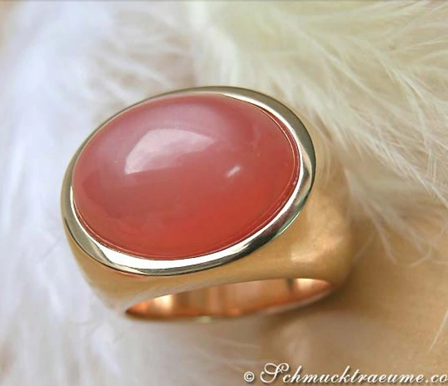 Goldener Ring mit ovalem rosa Mondstein auf flauschigem Hintergrund Goldener Ring mit ovalem rosa Mondstein auf flauschigem Hintergrund
