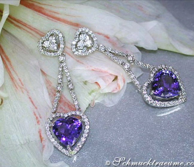 Herzformige Tansanit-Ohrringe mit Diamanten auf weißgoldener Basis, elegant auf Blüte platziert. Herzformige Tansanit-Ohrringe mit Diamanten auf weißgoldener Basis, elegant auf Blüte platziert.