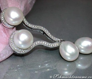 Geschwungene Süßwasserperlen-Ohrhänger mit Brillanten, detailreich, elegant, vor rosa Schleife.