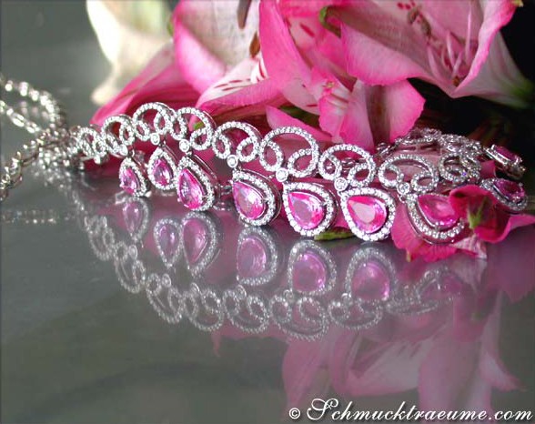 Pink-Saphir-Collier mit Brillanten, detailreiches Design, reflektierender Oberfläche, Blumen im Hintergrund.