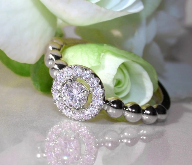 Weißgoldener Diamantring mit Kugel-Detail, Rosenblüte im Hintergrund Weißgoldener Diamantring mit Kugel-Detail, Rosenblüte im Hintergrund