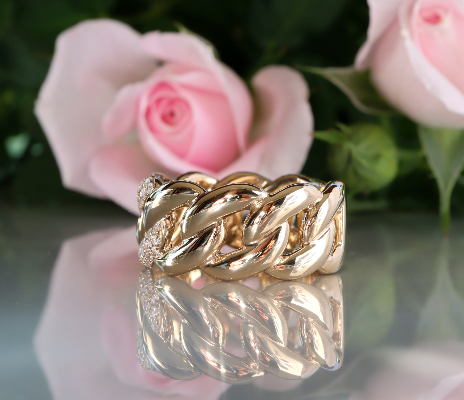 Goldener Panzerketterring mit Brillanten, detailreich, Rosen im Hintergrund