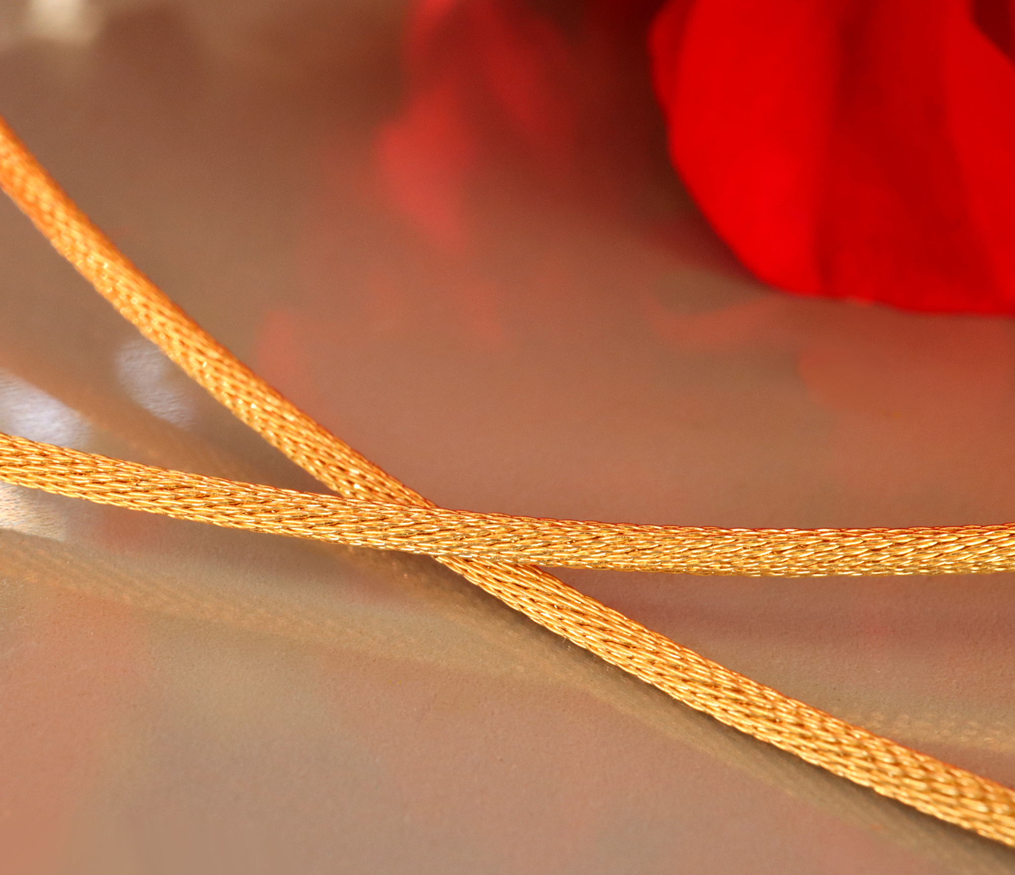 Detailaufnahme des gelbgoldenen Halsreifknotens mit feinen Fäden