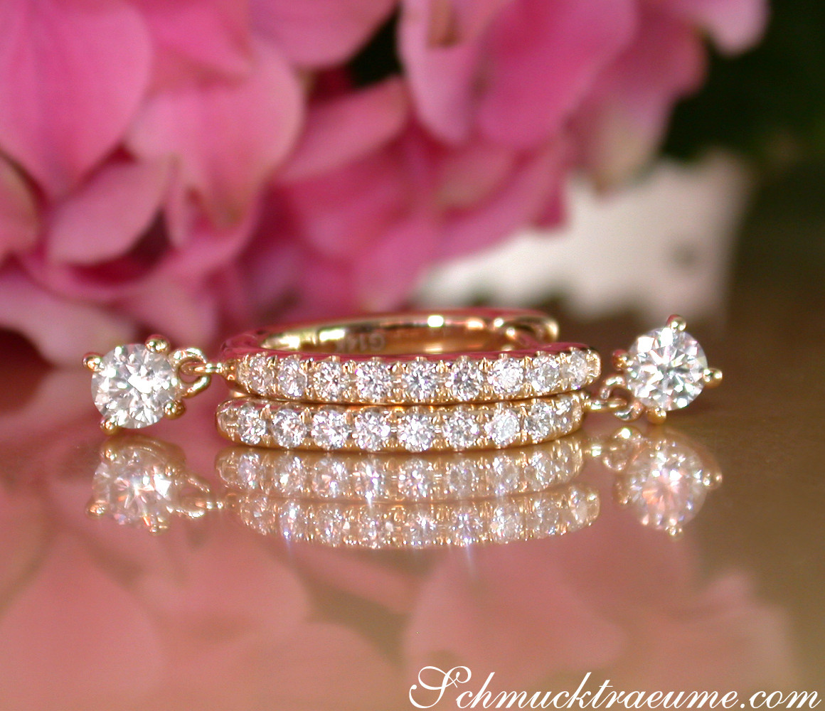 Goldene Creolen mit funkelnden Brillanten vor rosa Blüten