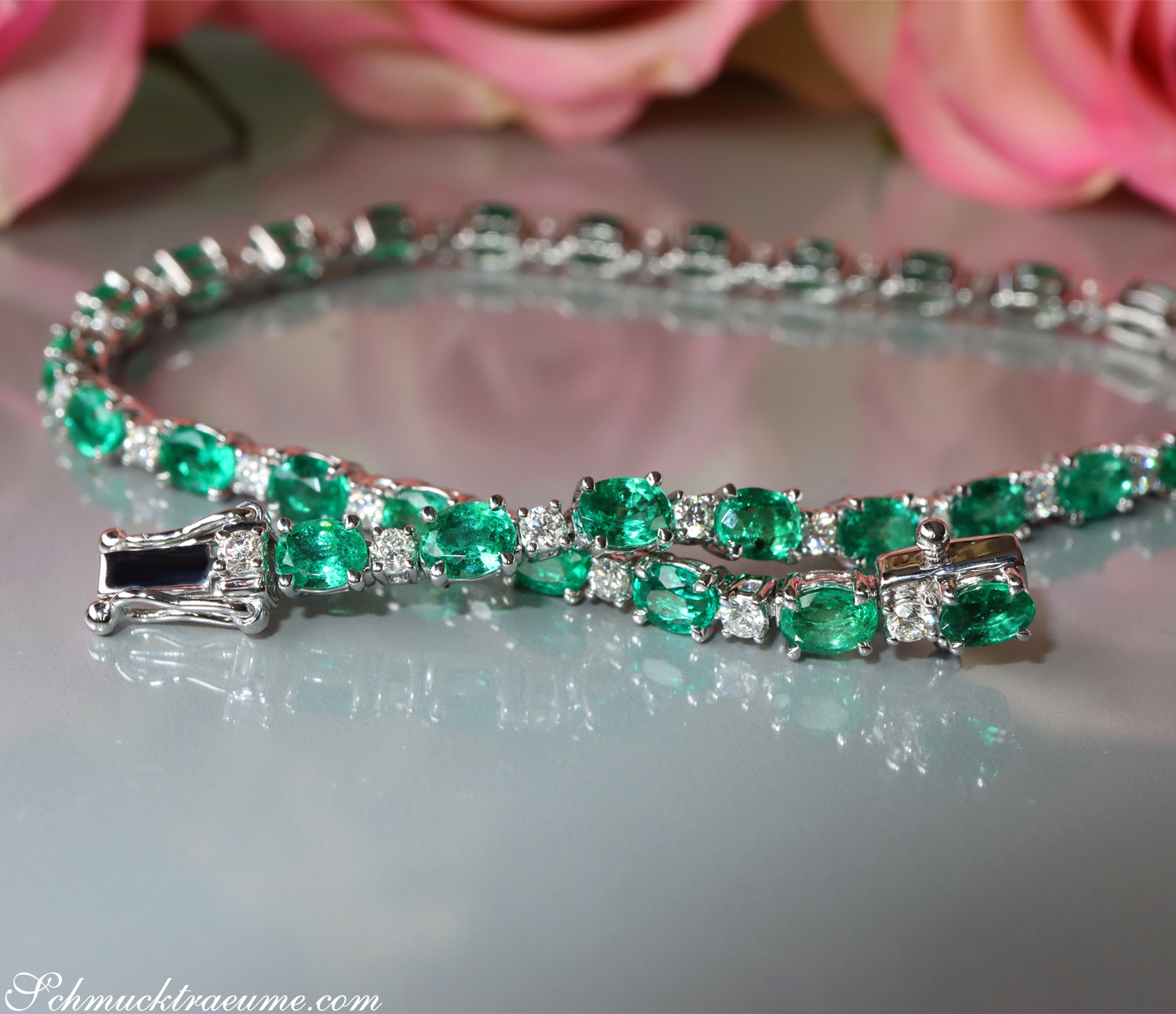 Smaragd-Armband mit Brillanten auf Spiegeloberfläche, detailreich, rosa Rosen im Hintergrund.
