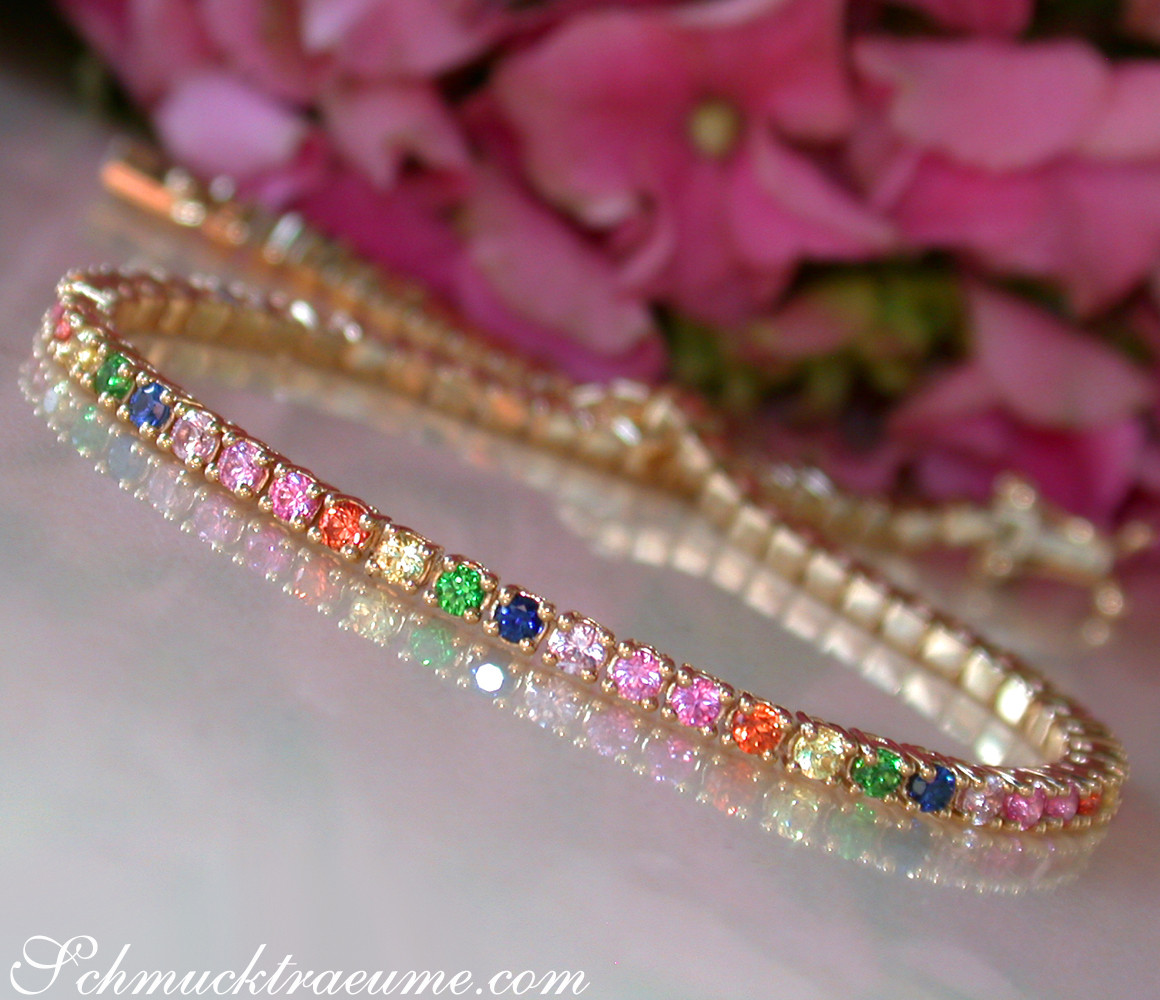 Gelbgold-Armband mit farbenfrohen Saphiren, Detailaufnahme, Rosen im Hintergrund